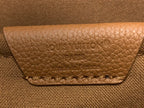 Louis Vuitton logo patch on tan leather flap with stitched edge