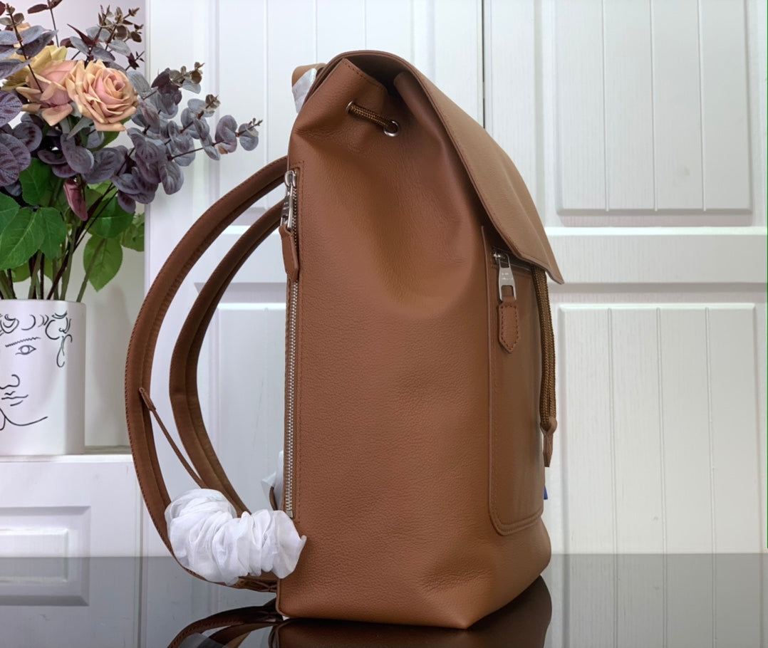 Louis Vuitton tan leather backpack side view with shoulder strap and metal details