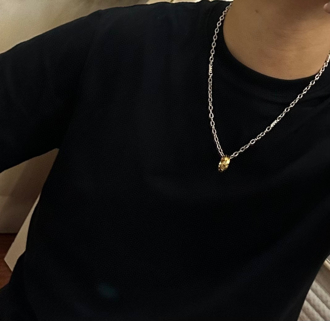 Silver-tone chain necklace with small gold-tone pendant on dark top