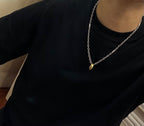Silver-tone chain necklace with small gold-tone pendant on dark top