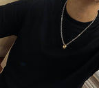 Silver-tone chain necklace with gold-tone pendant on dark top