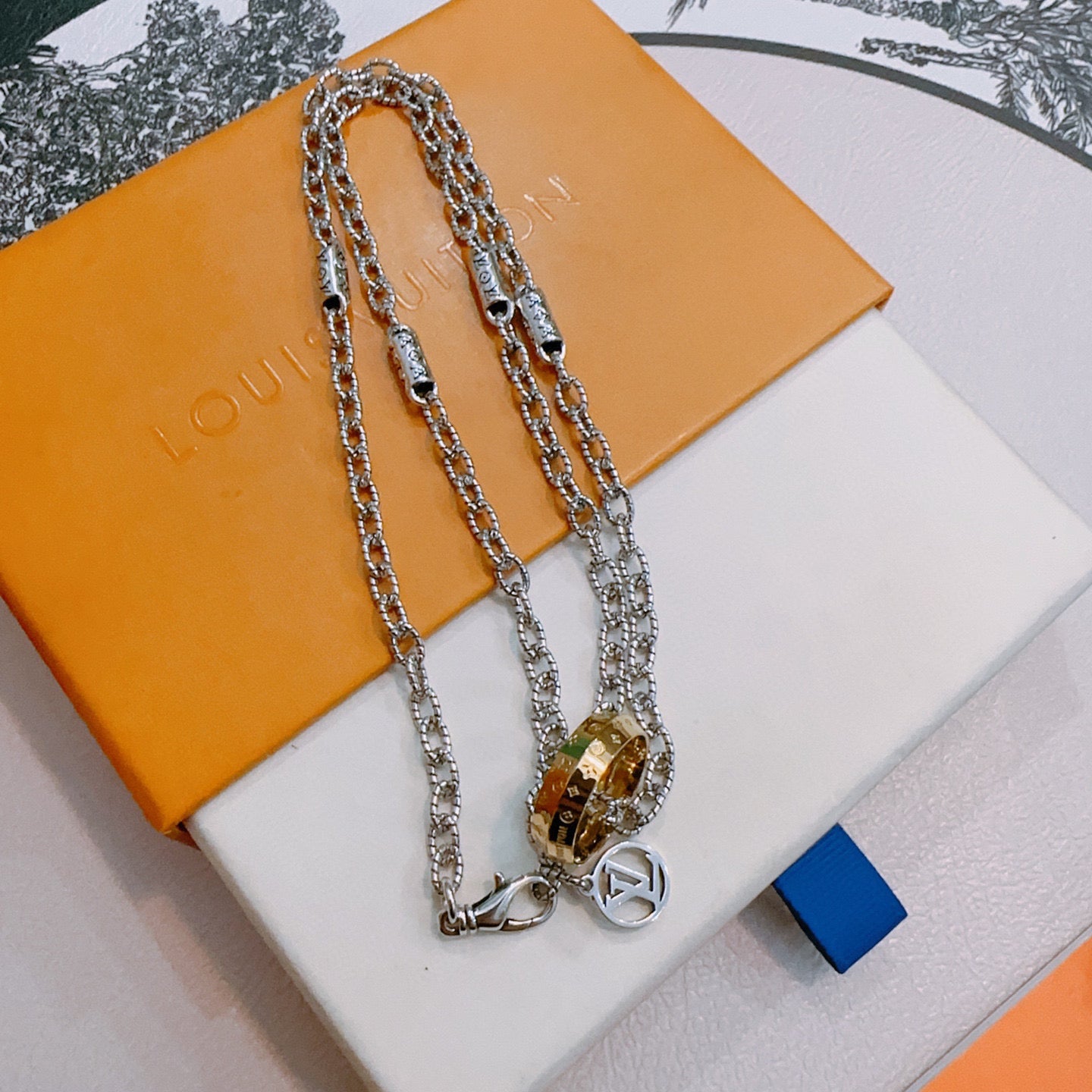 Silver-tone layered chain necklace with gold-tone lock pendant and ring charm