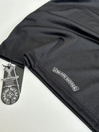 Chrome short long-sleeve jersey fabric close-up with small logo patch and tag in dark charcoal
