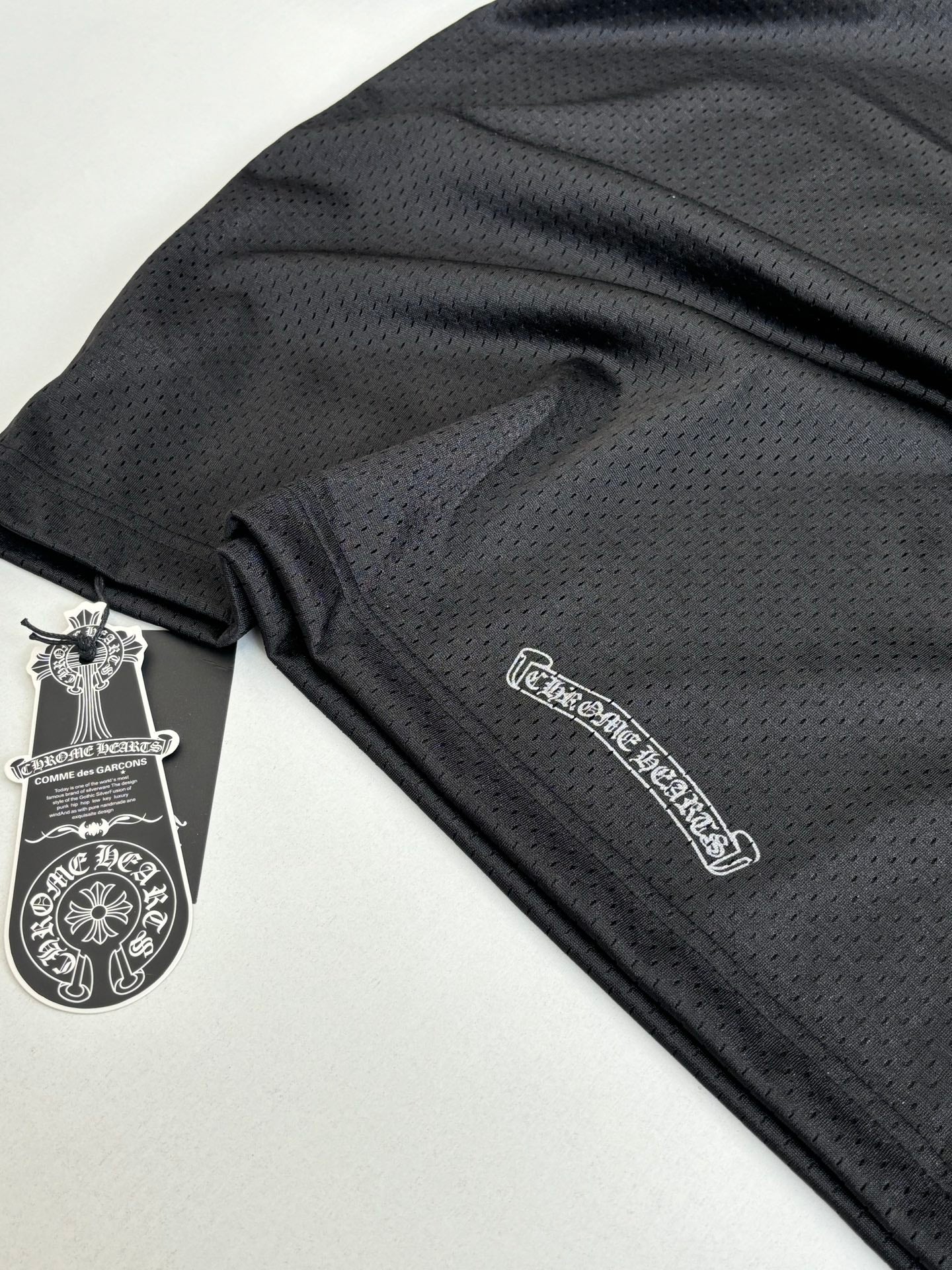 Chrome short long-sleeve jersey fabric close-up with small logo patch and tag in dark charcoal