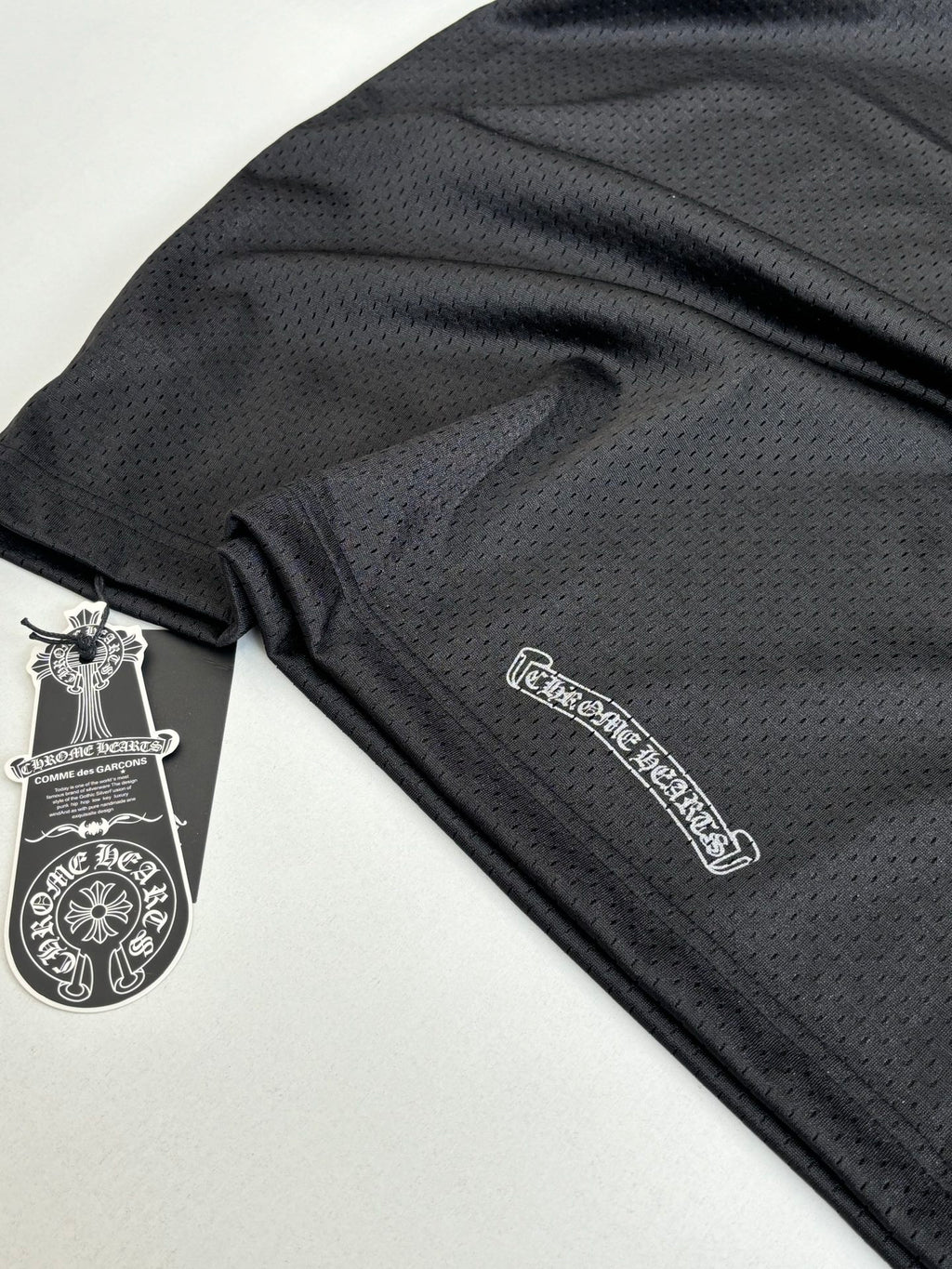 Black textured long-sleeve top with small logo patch on sleeve hem.