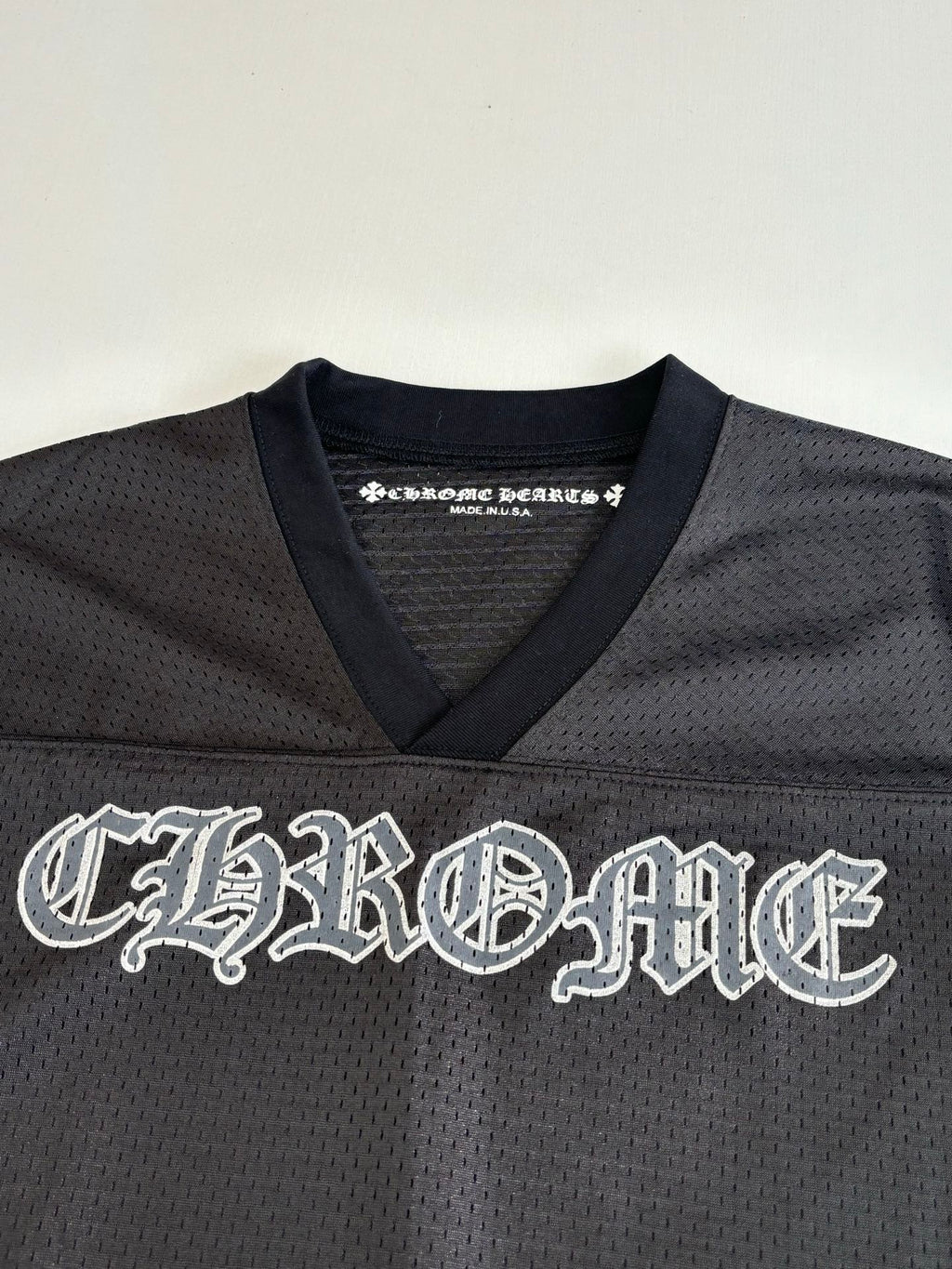 Chrome short long-sleeve jersey top front close-up with large embroidered-style logo in dark charcoal