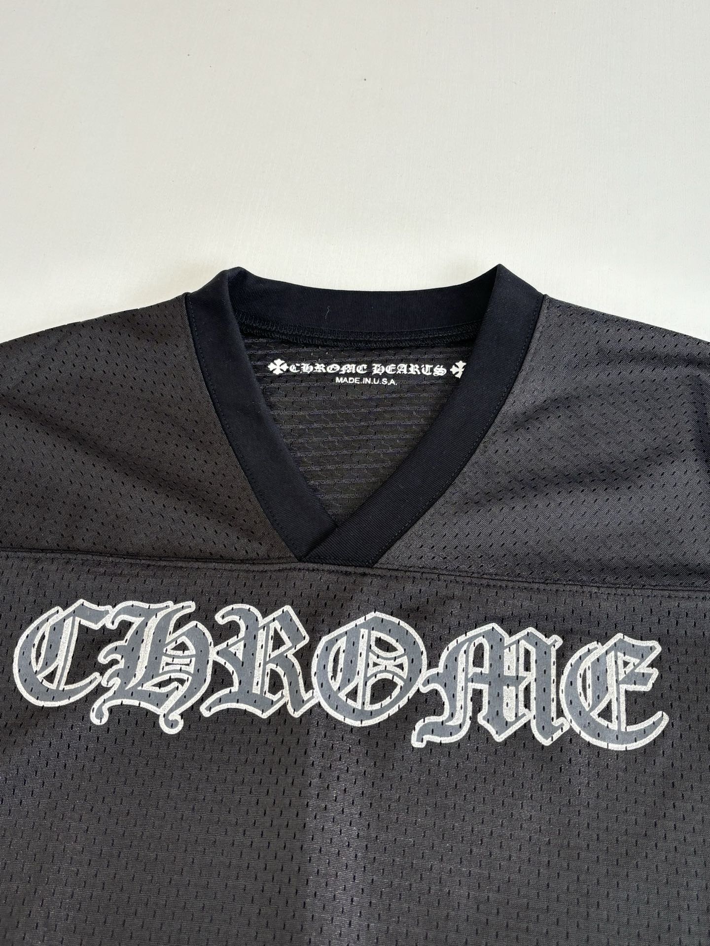 Chrome short long-sleeve jersey top front close-up with large embroidered-style logo in dark charcoal