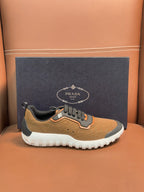 Tan and black lace-up sneakers with orange trim and white outsole, Prada emblem on side