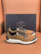 Tan lace-up sneakers with black overlays, orange trim, and white chunky sole, Prada