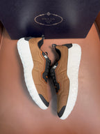 Tan and black lace-up sneakers with orange accents and white rubber soles, Prada details