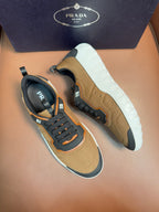 Tan and black lace-up sneakers with orange trim, thick white outsole, Prada logo tab