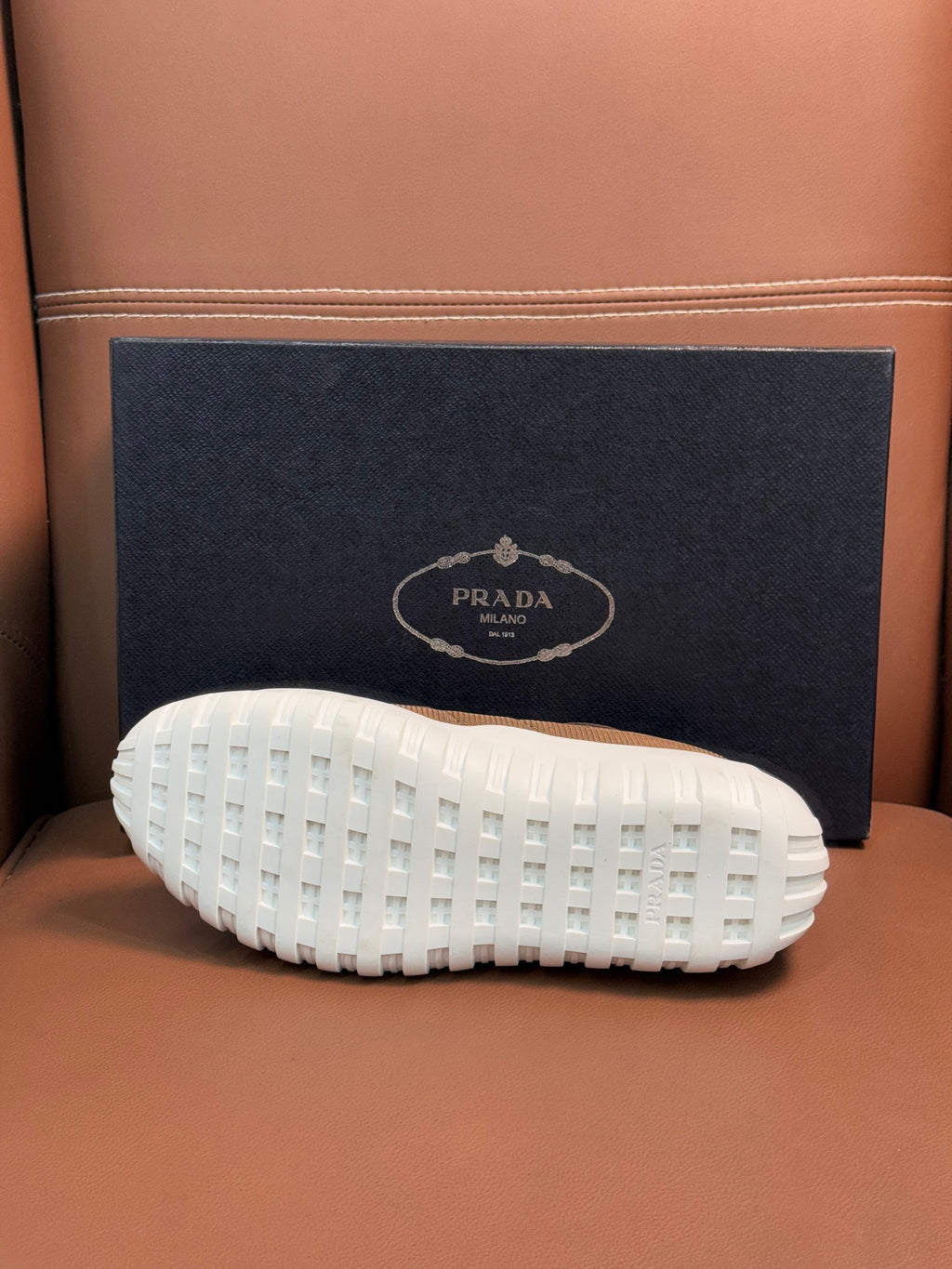 White tread outsole of tan and black sneaker, with Prada logo on heel panel