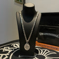 Silver-tone chain necklace with oval medallion pendant on black display bust.