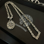 Silver-tone chain necklace with oval medallion pendant laid on black box surface.