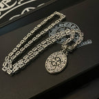 Silver-tone chain necklace with oval medallion pendant on black box insert, side angle.
