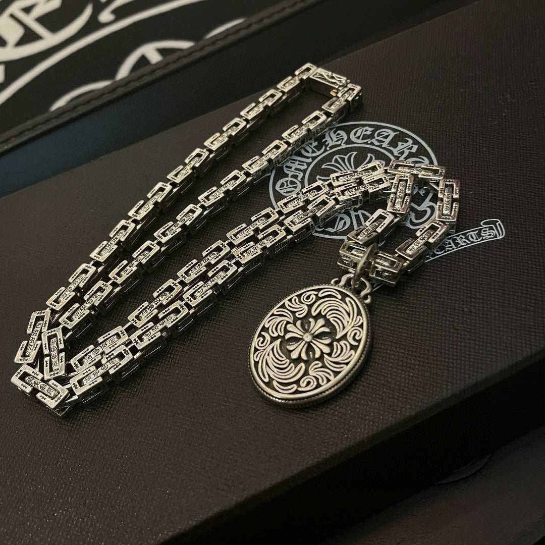 Silver-tone chain necklace with oval medallion pendant on black box insert, side angle.