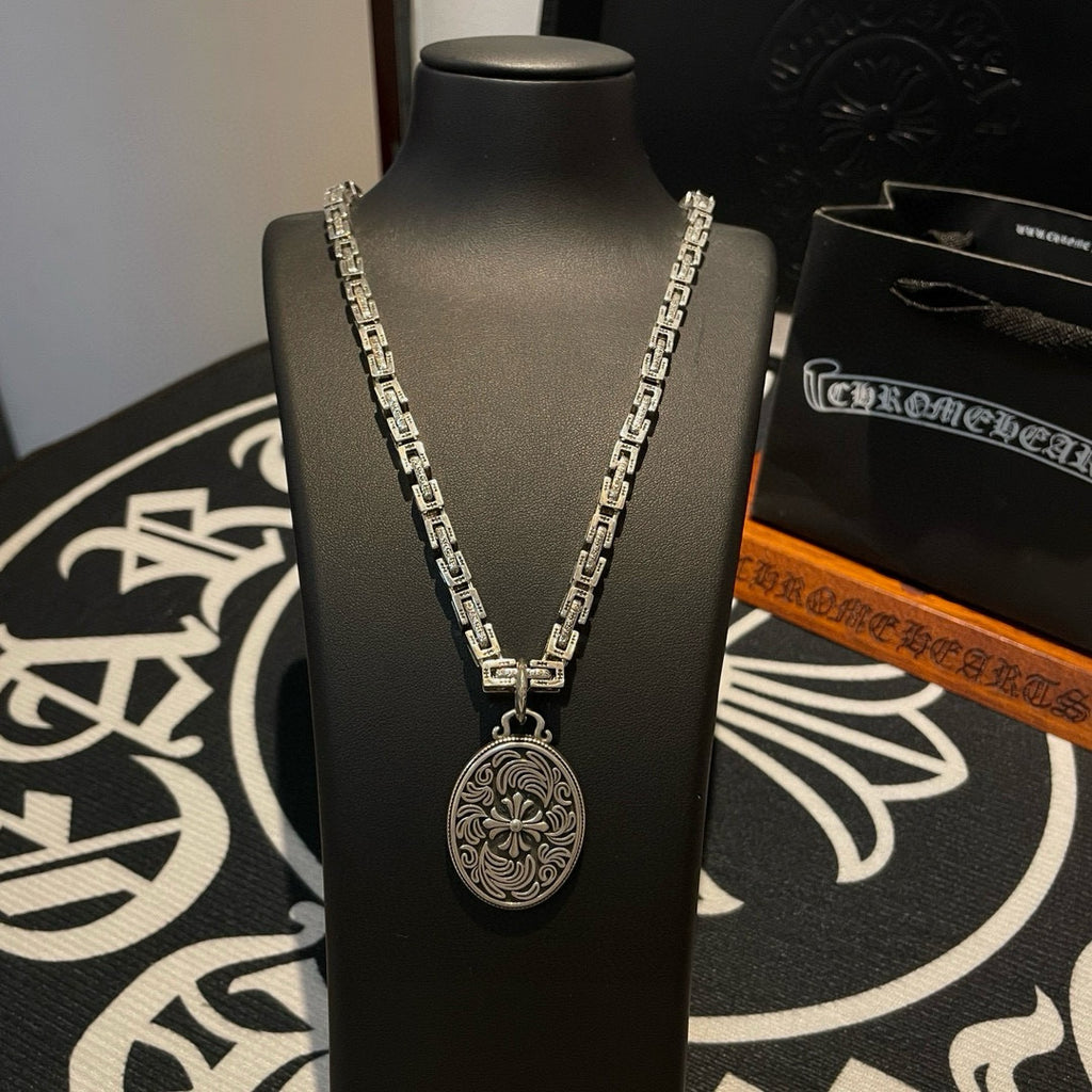 Silver-tone chain necklace with oval medallion pendant shown on display bust.