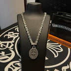 Silver-tone chain necklace with oval medallion pendant shown on display bust.