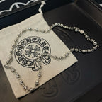 Silver ball chain necklace on a drawstring pouch beside a matching chain.