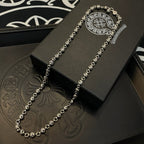 Silver long necklace with circular charm center on a black jewelry box.