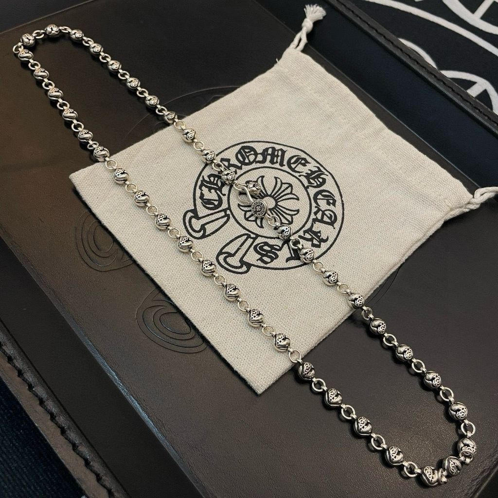 Silver ball chain necklace resting on a black box with a light drawstring bag.