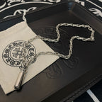 Chrome chain necklace with capsule pendant draped across a jewelry case insert