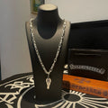 Silver-tone layered chain necklace with small cross-style charm on black display stand