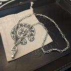 Silver-tone chain necklace with pendant charm on black box with small pouch