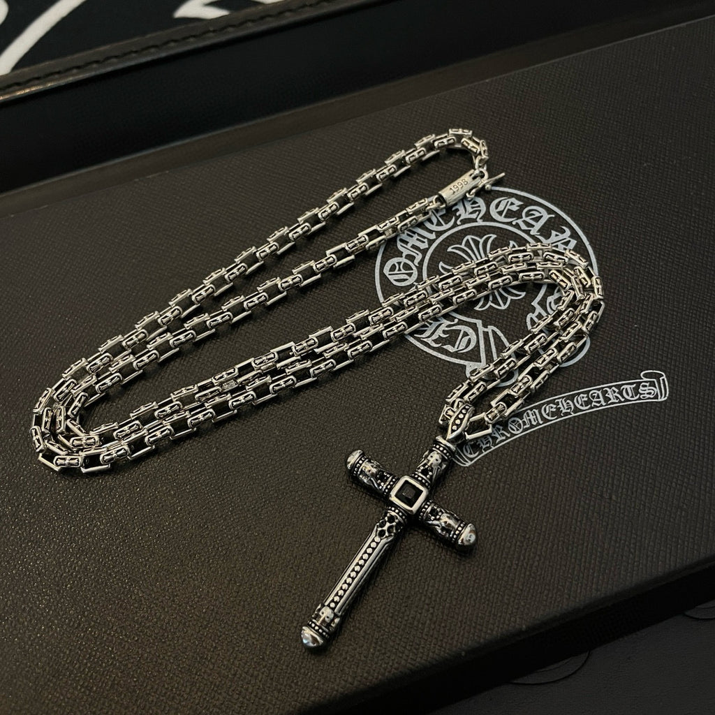 Silver-tone cross pendant necklace with chain links on black box base.