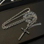 Silver-tone cross pendant necklace with chain links on black box base.
