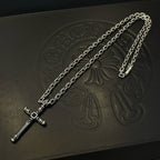 Silver-tone cross pendant necklace with chain links on embossed black box.