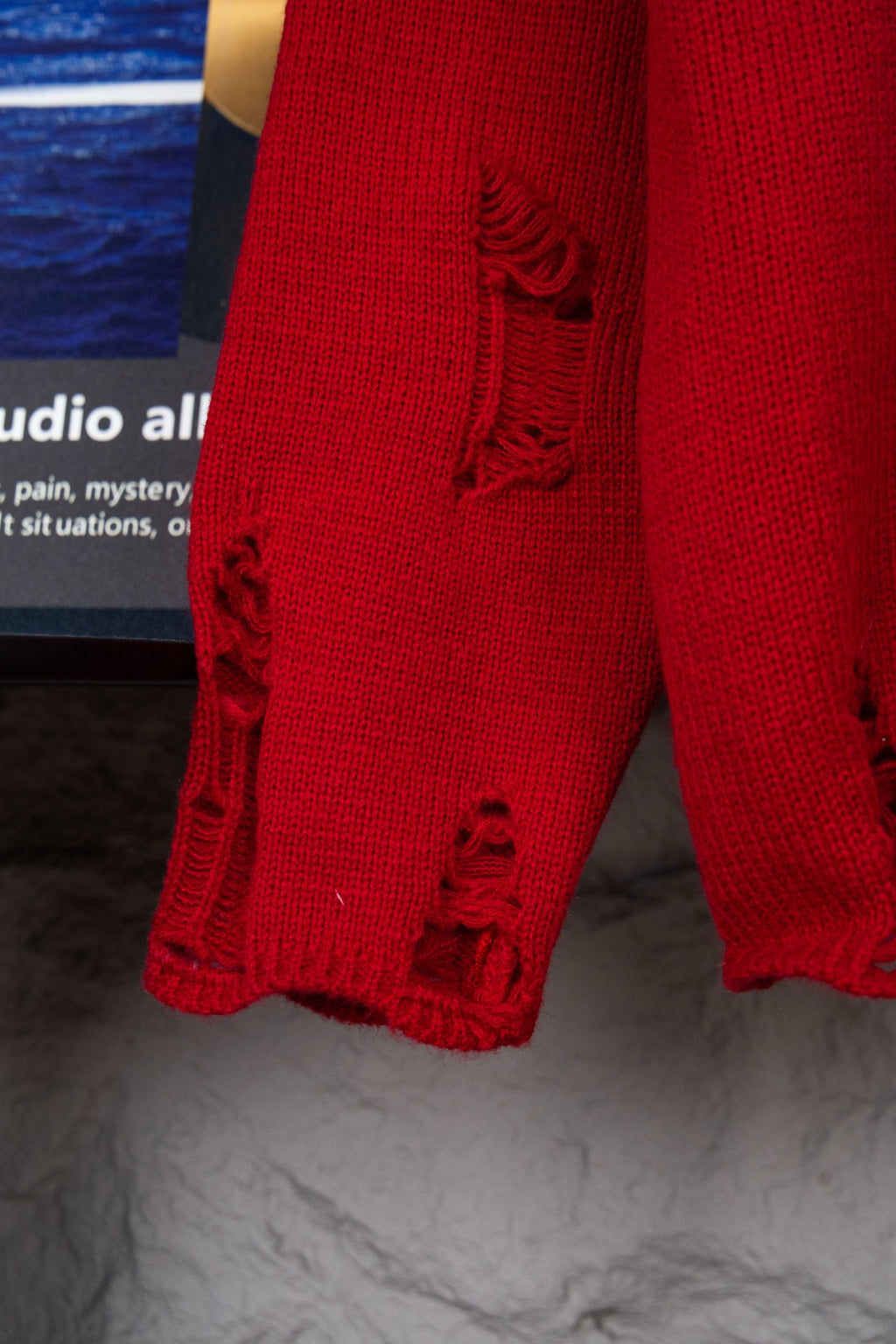 Red sweater sleeve cuff with black distressed embroidered detailing