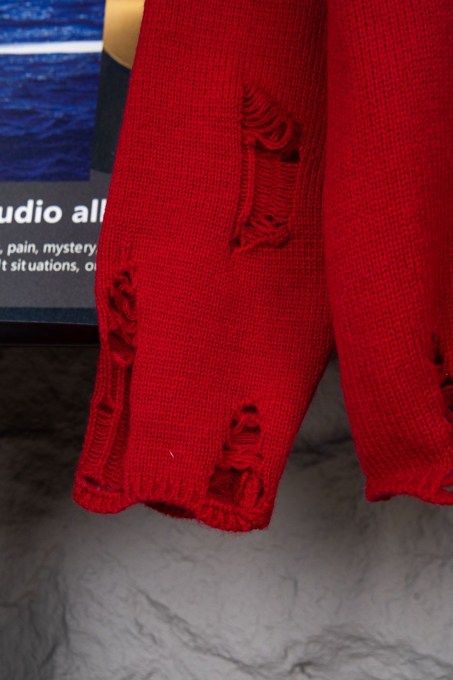 Red sweater sleeve cuff with black distressed embroidered detailing
