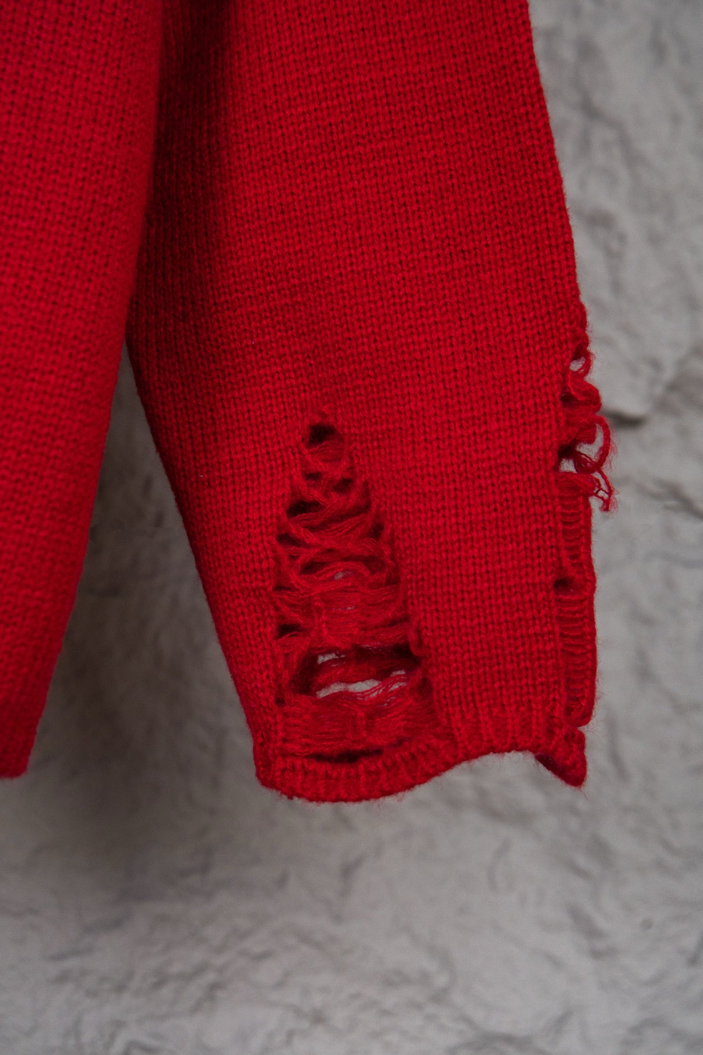 Red sweater sleeve hem with black stitched lace-up style embroidery