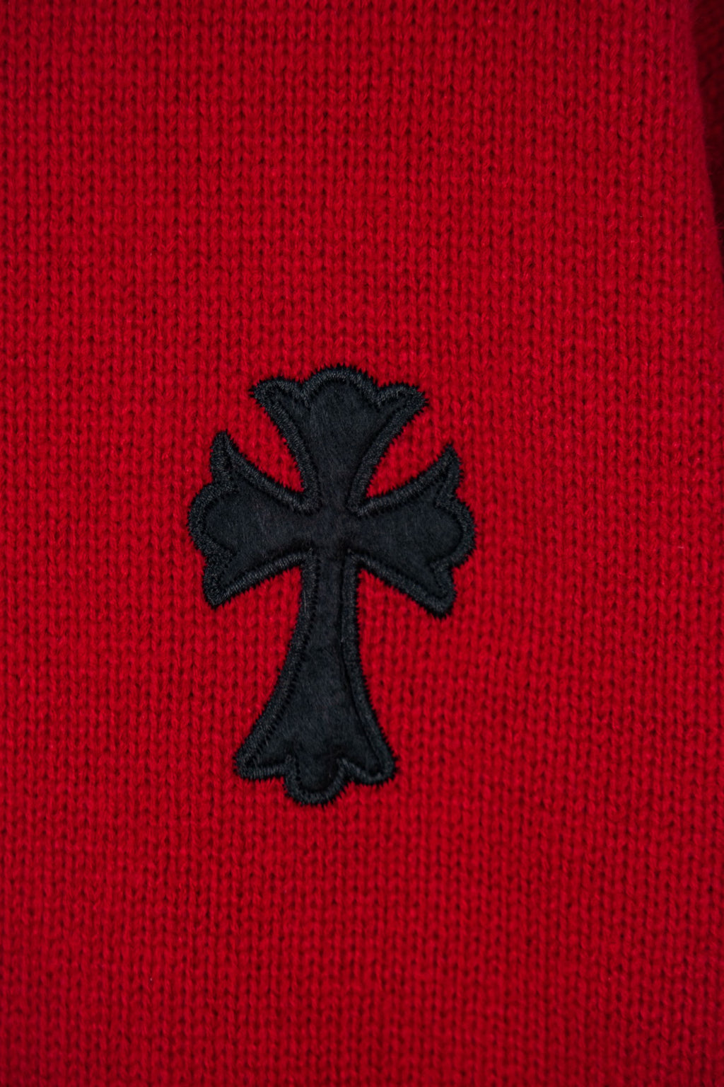 Red sweater with black cross applique embroidered on the front