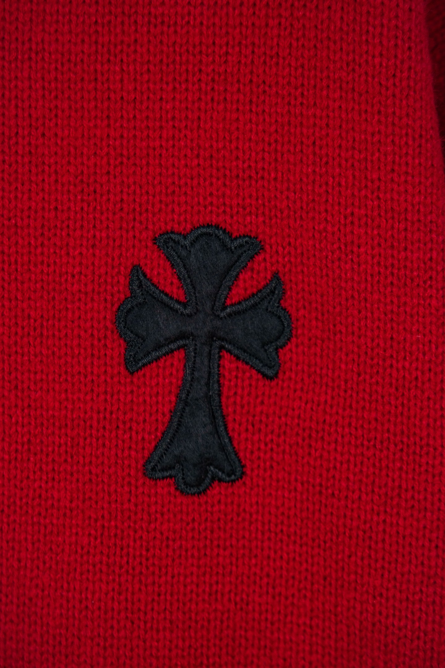 Red sweater with black cross applique embroidered on the front