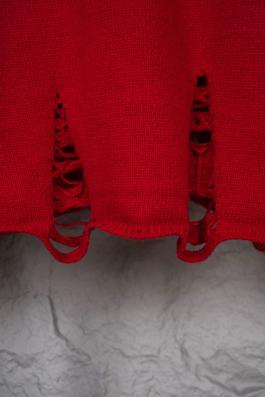 Red sweater hem with black distressed embroidery cutout details