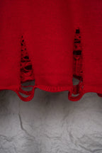 Red sweater hem with black distressed embroidery cutout details