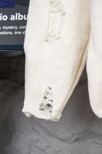 Cream sweater sleeve with ribbed cuff and distressed, cutout detailing