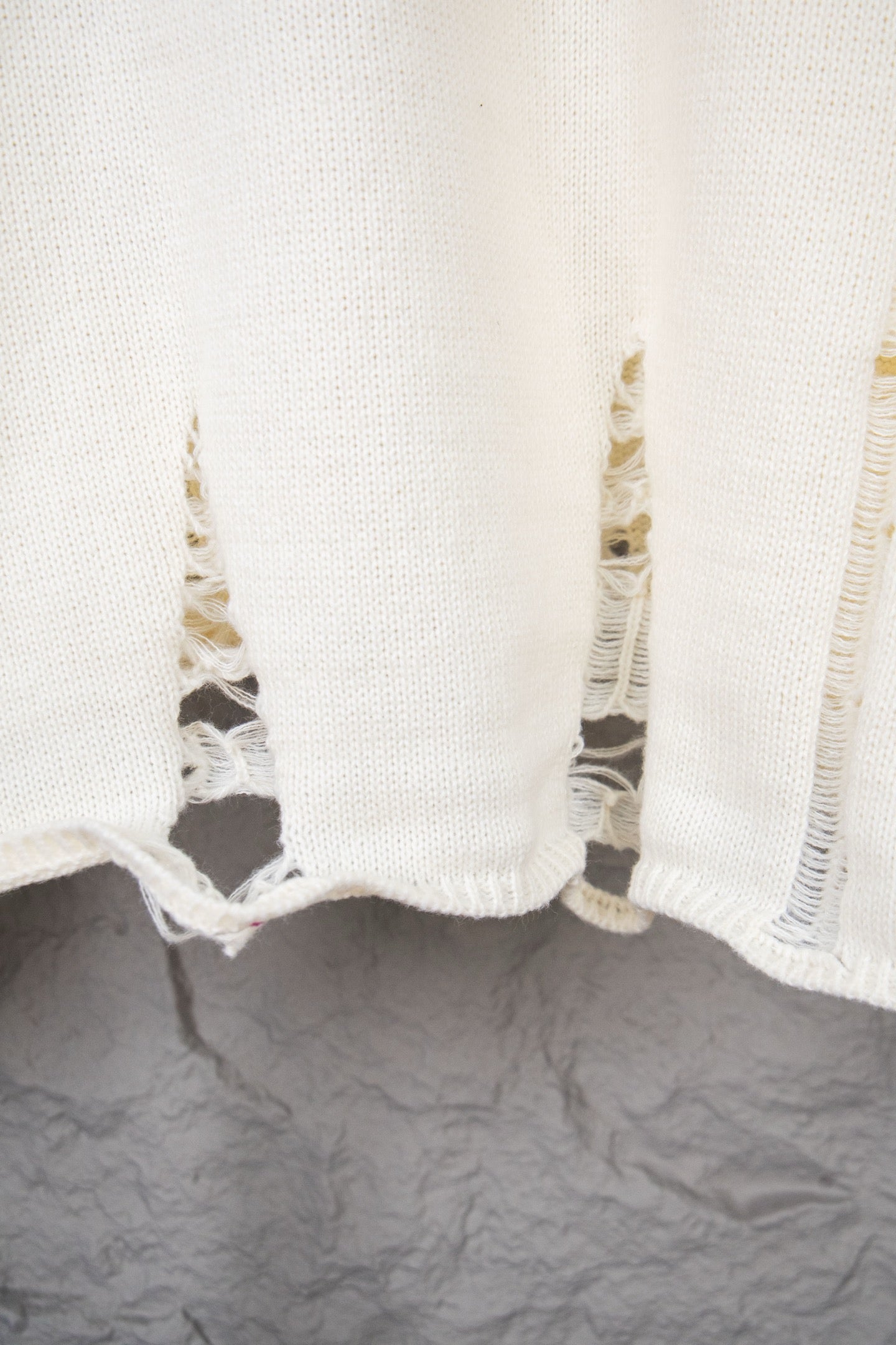 Cream sweater hem and sleeve cuff with frayed distressed edges