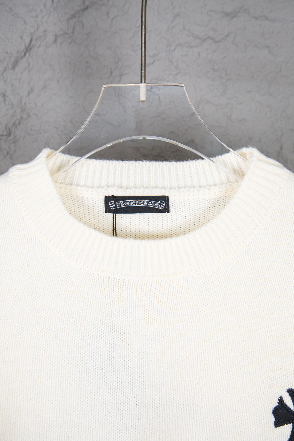 Cream knit sweater neckline with ribbed crewneck and hanging tag