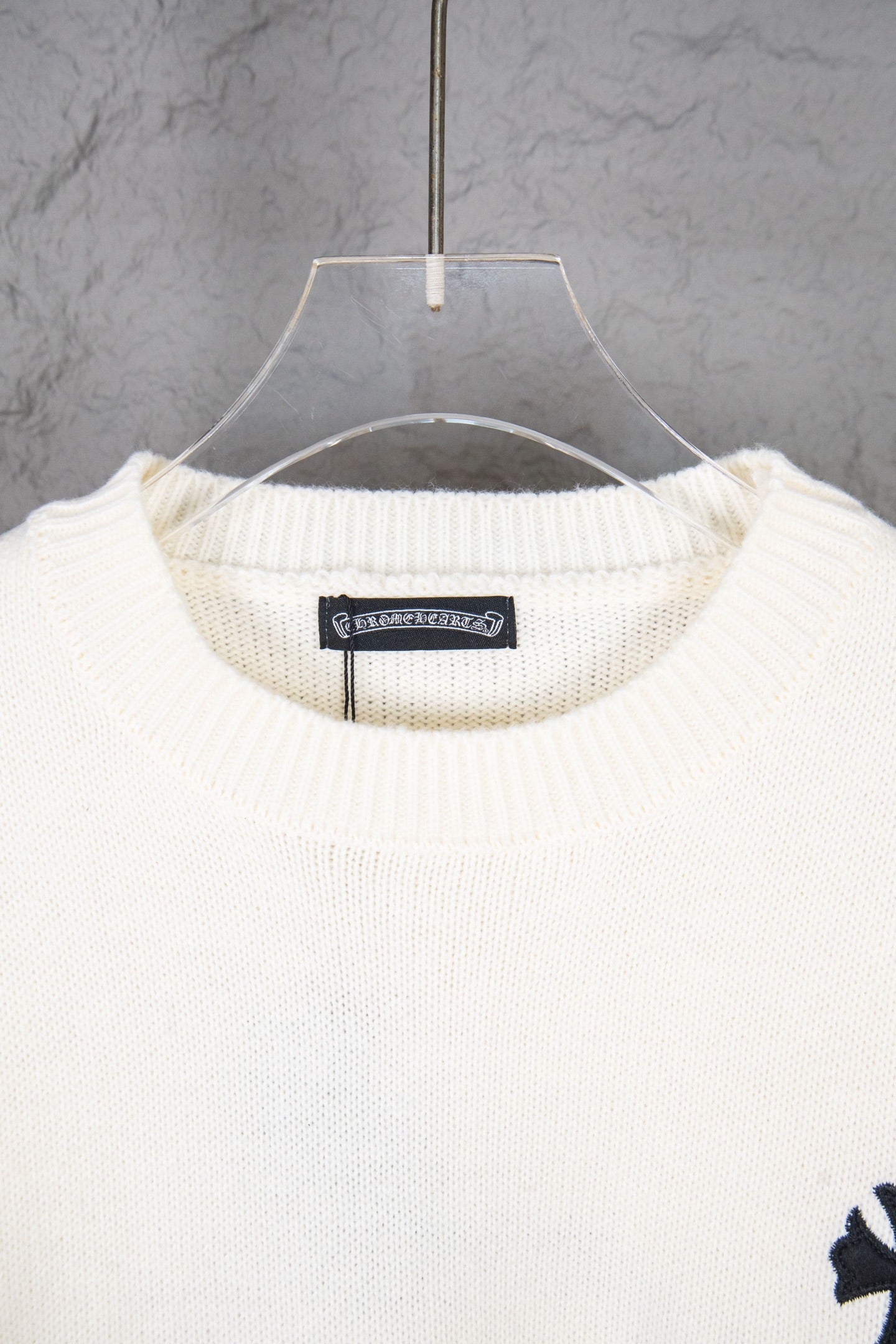 Cream knit sweater neckline with ribbed crewneck and hanging tag