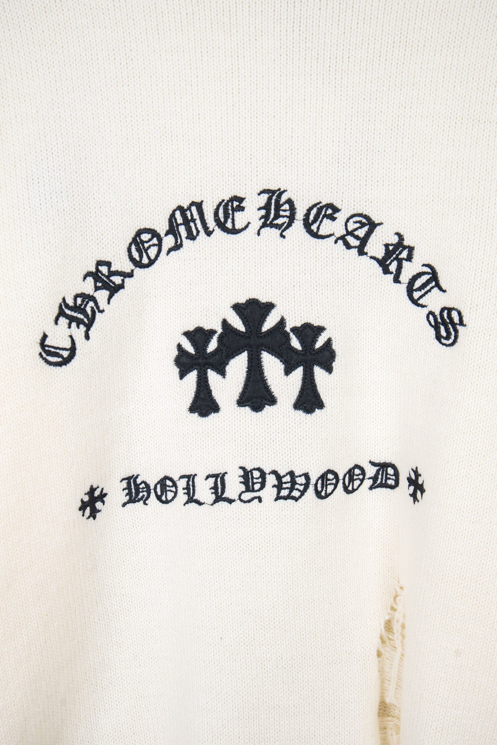 Cream long-sleeve sweater front with dark graphic and crosses