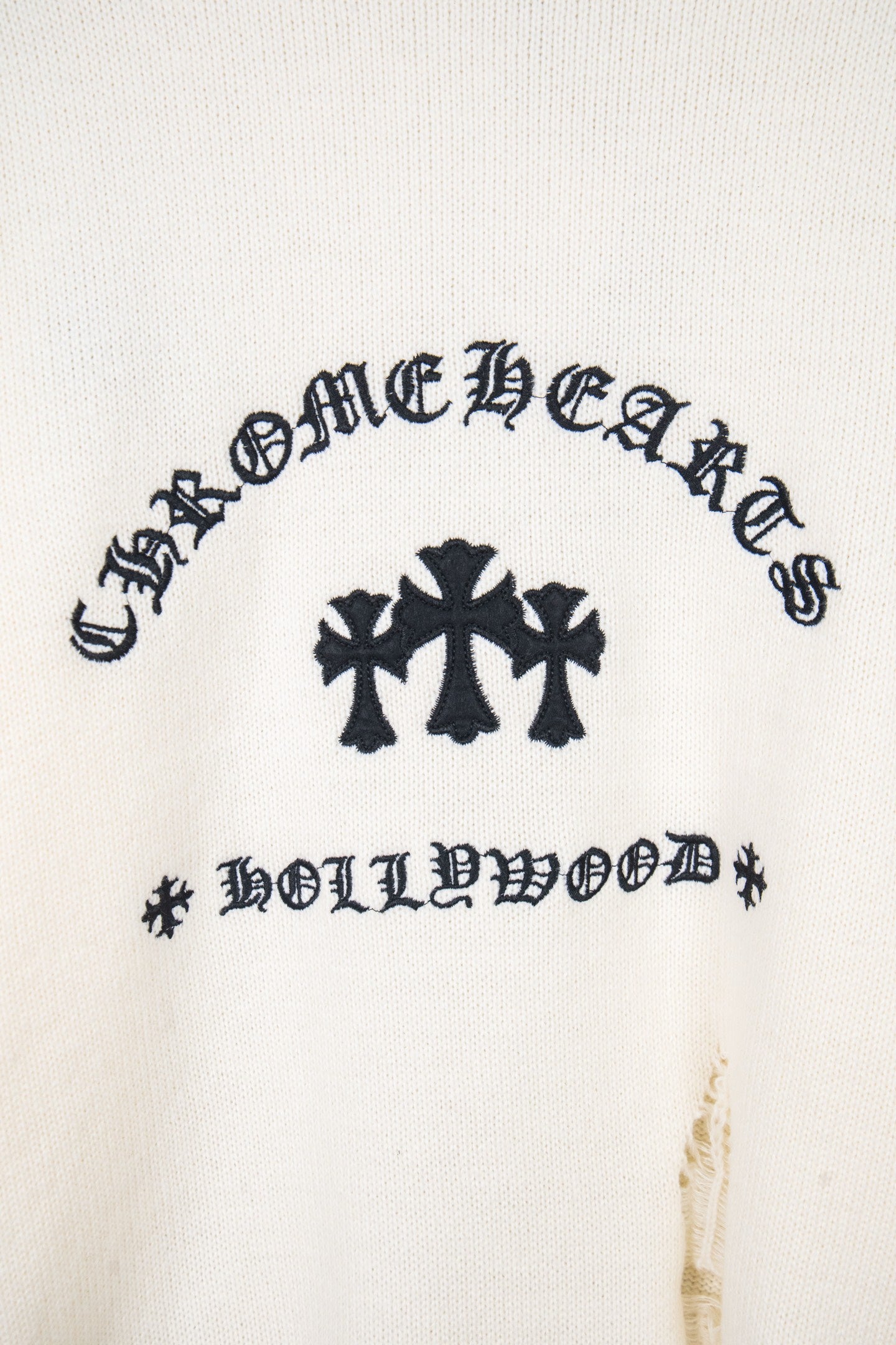 Cream long-sleeve sweater front with dark graphic and crosses