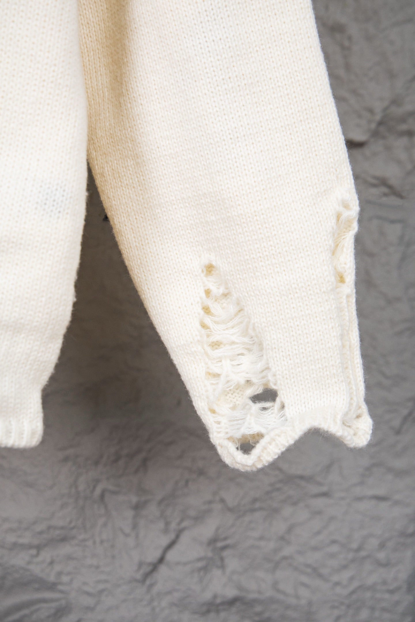 Cream sweater body with ribbed hem and distressed fabric patch