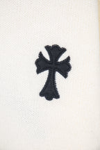 Cream sweater sleeve with black cross appliqué