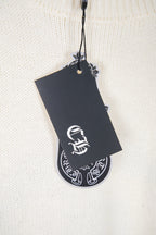 Cream knit sweater close-up with black logo hang tag