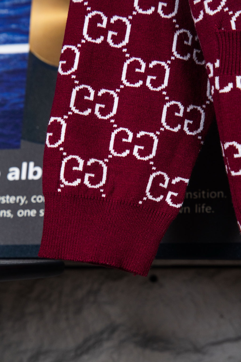 Gucci knit sweater sleeve hem on burgundy fabric with repeating white GG pattern