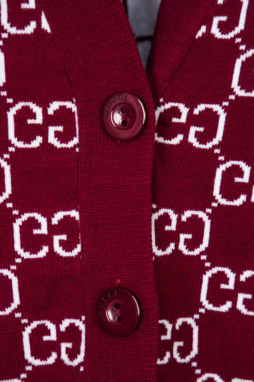 Gucci knit sweater button placket on burgundy fabric with white GG logo pattern