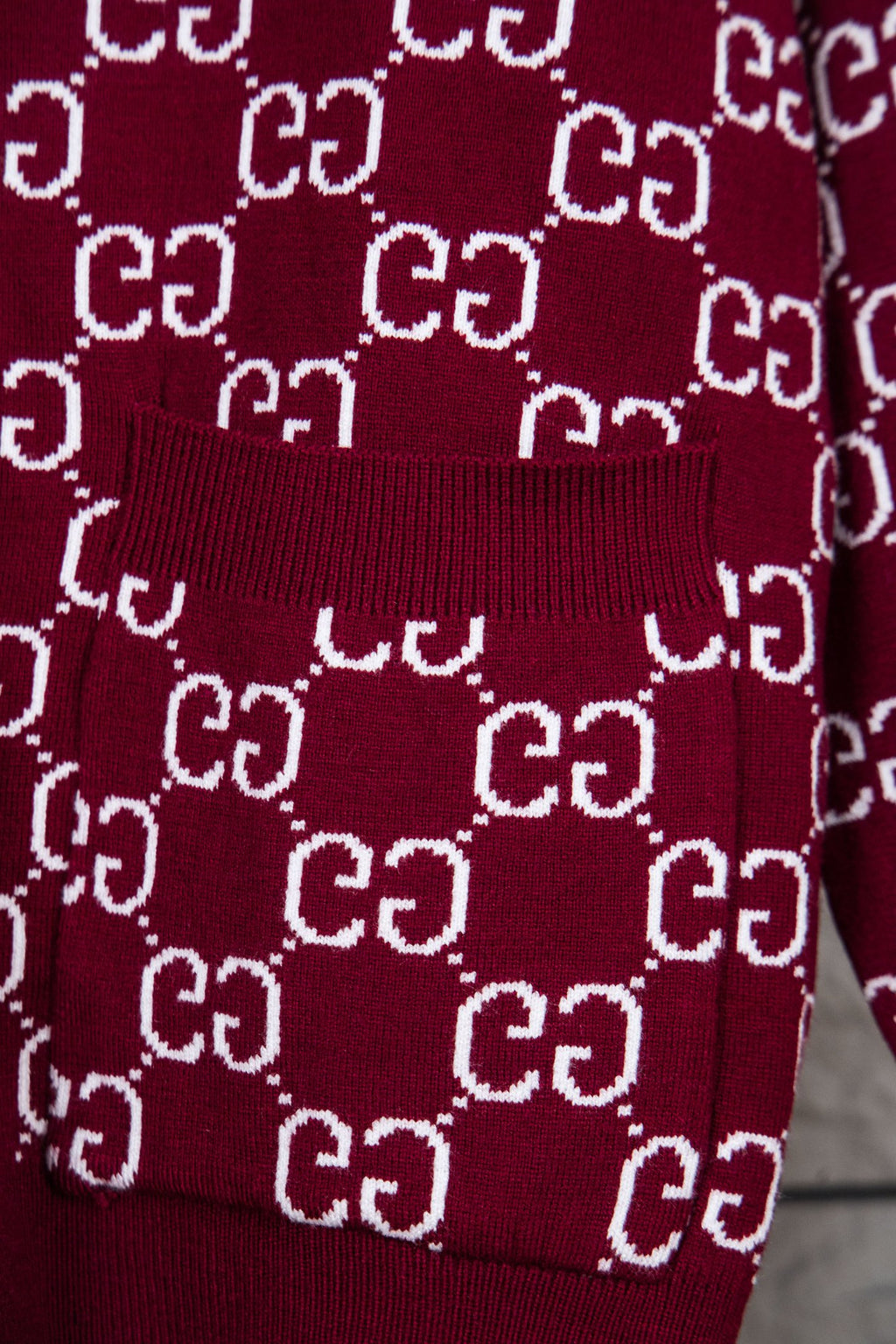 Gucci knit sweater with ribbed cuff and hem on burgundy fabric; white GG pattern